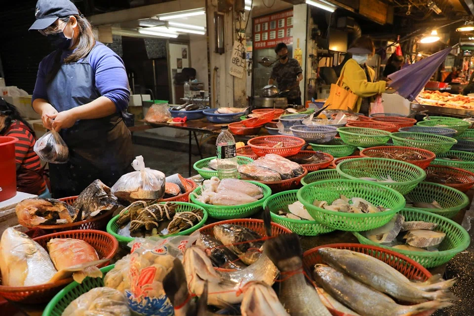 A woman wearing a face mask works at a fish stall in a market in Taipei, Taiwan, 26 November 2021. (Annabelle Chih/Reuters)