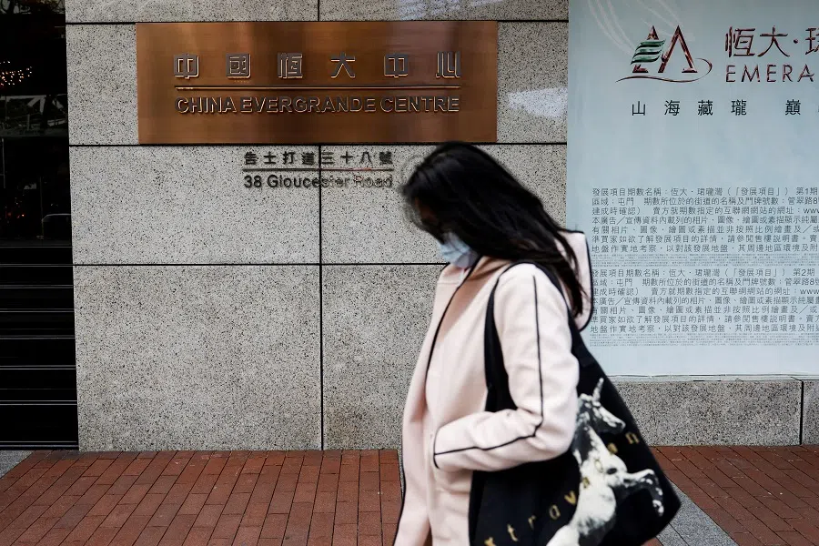 A woman walks in front of the China Evergrande Centre building sign in Hong Kong, China, on 7 December 2021. (Tyrone Siu/Reuters)