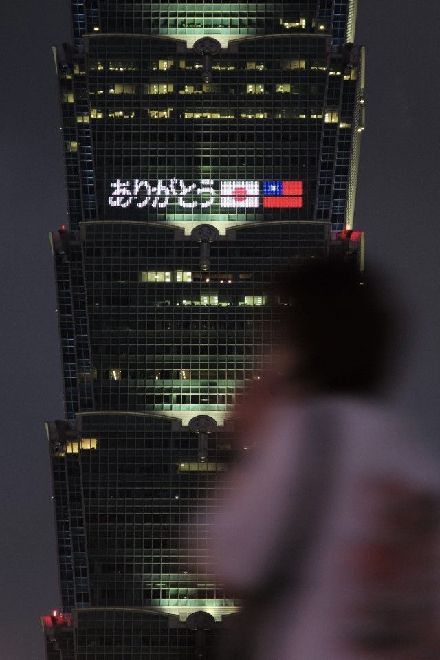A woman walks past the Taipei 101, a 508- meter high's commercial building, with the LED lights reading "tribute to Japanese prime minister Abe Shinzo for Taiwan's friendship" in Taipei on 9 July 2022. (Sam Yeh/AFP)