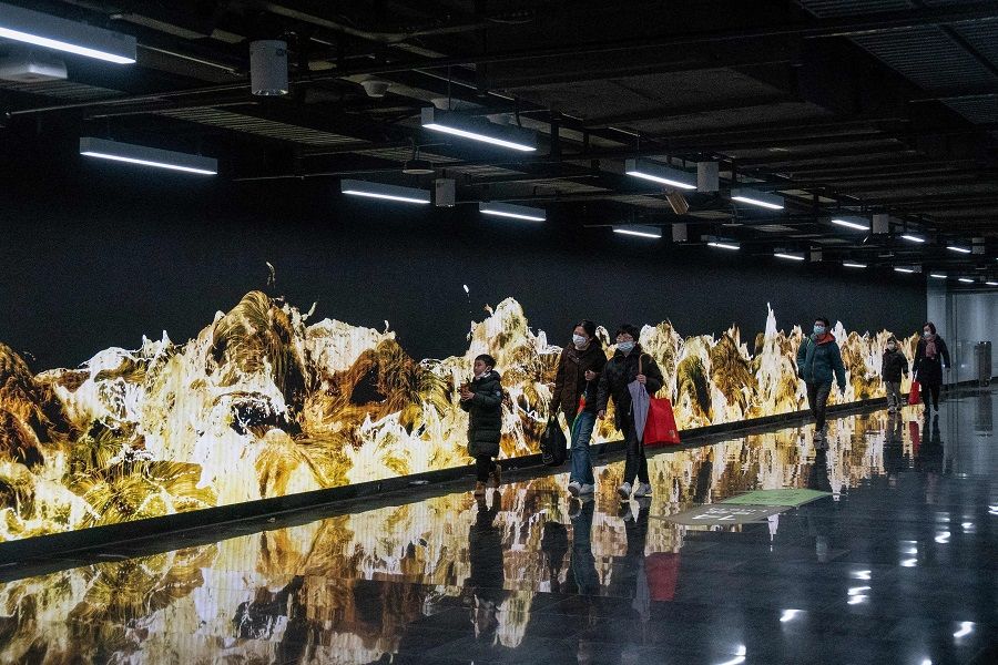 People walk past a 112-metre-long installation entitled "Gold Waves" by teamLab at Shanghai's Lujiazui sbuway station in China on 26 January 2022. (AFP)