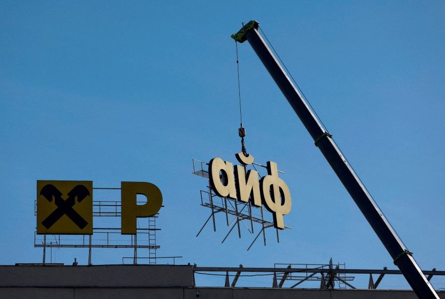 Workers use a crane to dismantle a signboard advertising Austria’s Raiffeisen Bank from a building in Moscow, Russia, on 14 April 2023.  (Maxim Shemetov/Reuters)