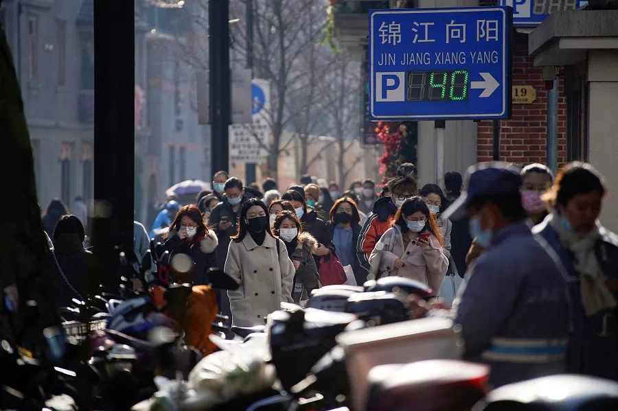 People wearing face masks walk on a street in Shanghai, China, 13 December 2022. (Aly Song/Reuters)