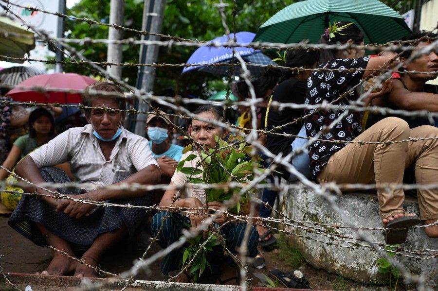 People wait for detainees to be released from Insein Prison in Yangon on 19 October 2021, after authorities let out thousands of people jailed for protesting against a February coup that ousted the civilian government. (STR/AFP)