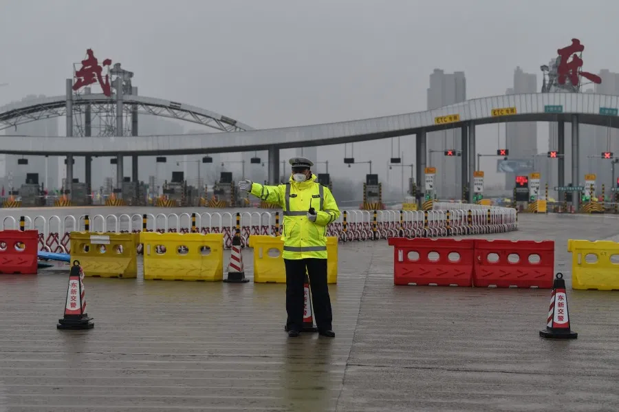 An officer gestures in front of one of the roads blocked by the police to restrict people leaving Wuhan. (Hector Retamal/AFP)