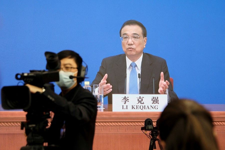 Chinese Premier Li Keqiang is seen on a screen as he attends a news conference via video link in Beijing, China, 11 March 2022. (Ryan Woo/Reuters)