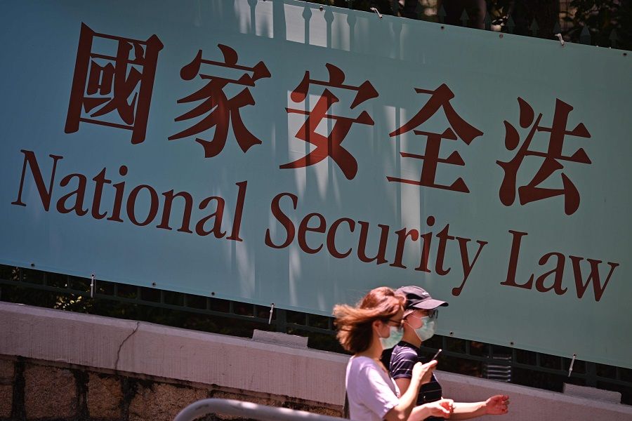 Pedestrians walk past a government public notice banner for the National Security Law in Hong Kong on 15 July 2020. (Anthony Wallace/AFP)