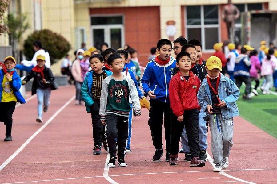 Students walk along a playground at an elementary school in Qingdao, Shandong province, China on 11 May 2021. (STR/AFP)