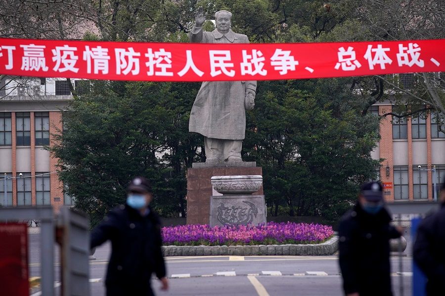 Security guards wearing protective masks are seen in front of a statue of former Chinese leader Mao Zedong at Tongji University amid the Covid-19 pandemic, in Shanghai, China on 12 March 2020. (Aly Song/Reuters)