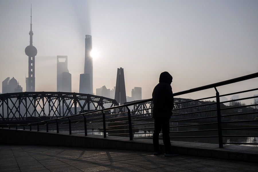 A pedestrian along a bridge passes buildings in Pudong's Lujiazui Financial District in Shanghai, China, on 9 January 2024. (Qilai Shen/Bloomberg)