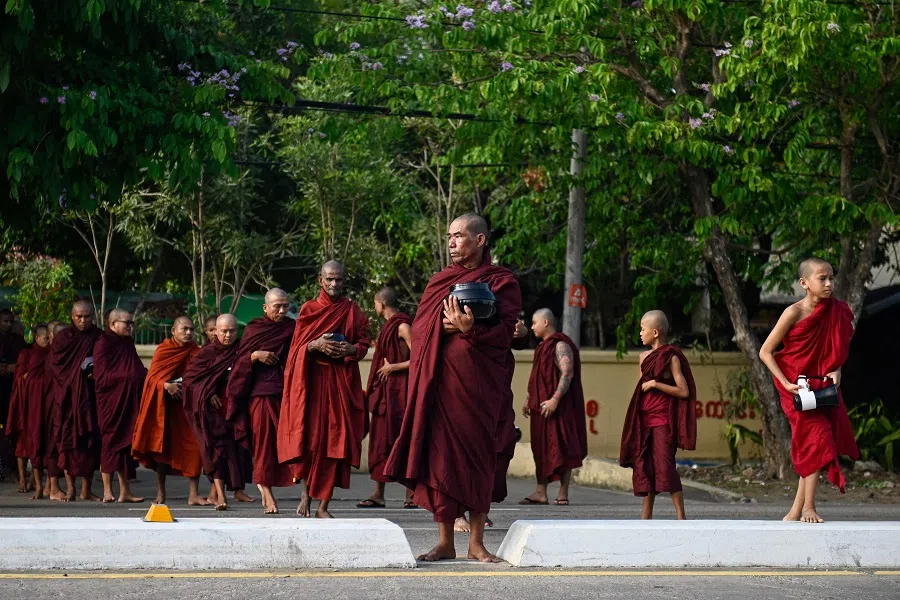 Buddhist monks cross a street to collect alms in Yangon on 17 April 2025. (Amaury Paul/AFP)
