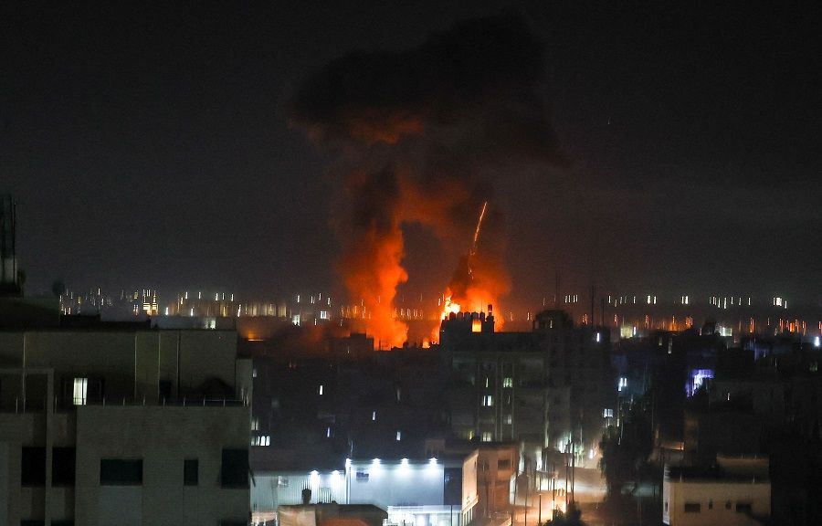 Explosions light up the night sky above buildings in Gaza City as Israeli forces shell the Palestinian enclave, early on 16 June 2021. (Mahmud Hams/AFP)
