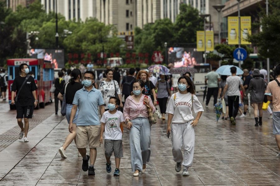 Pedestrians wearing protective masks walk down Nanjing East Road in Shanghai, China, on 14 August 2021. (Qilai Shen/Bloomberg)