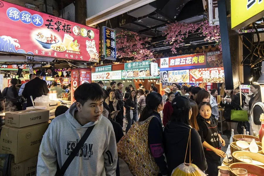 Pedestrians pass food stalls at the Dongmen Old Street shopping area in Shenzhen, China, on 18 January 2024. (Qilai Shen/Bloomberg)