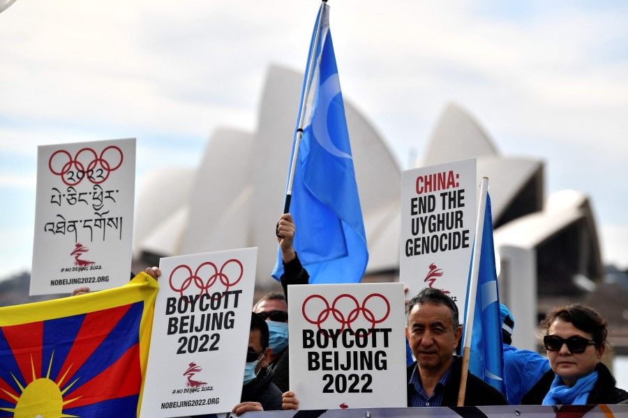 In this file photo taken on 23 June 2021 protesters hold up placards and banners as they attend a demonstration in Sydney to call on the Australian government to boycott the 2022 Beijing Winter Olympics over China's human rights record. (Saeed Khan/AFP)
