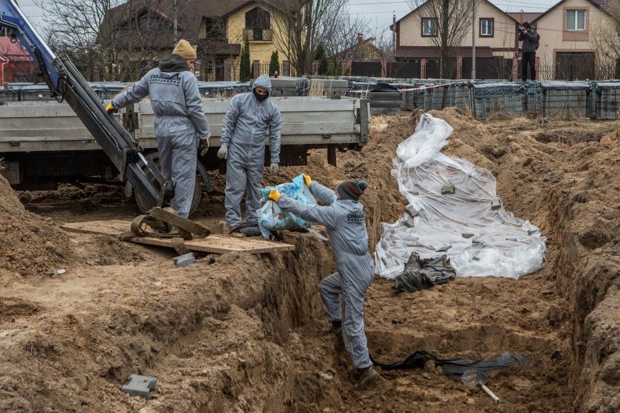 Forensic technicians exhume the bodies of civilians who Ukrainian officials say were killed during Russia's invasion and then buried in a mass grave in the town of Bucha, outside Kyiv, Ukraine, 13 April 2022. (Volodymyr Petrov/Reuters)