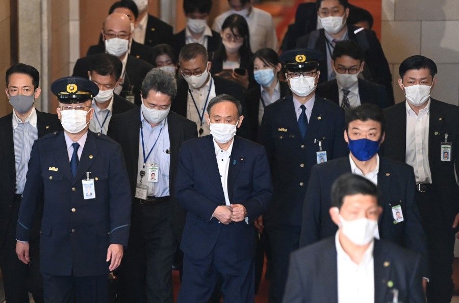 Japan's Prime Minister Yoshihide Suga (centre) leaves after a lower house budget committee session at parliament in Tokyo on 10 May 2021. (Kazuhiro Nogi/AFP)