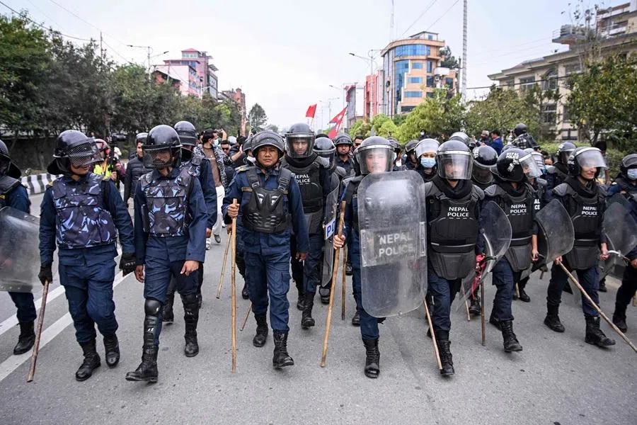 Police personnel stand guard as supporters of Nepal’s former prime minister Khadga Prasad Sharma Oli march during a protest against his arrest in Kathmandu on 30 March 2026. (Prakash Mathema/AFP)