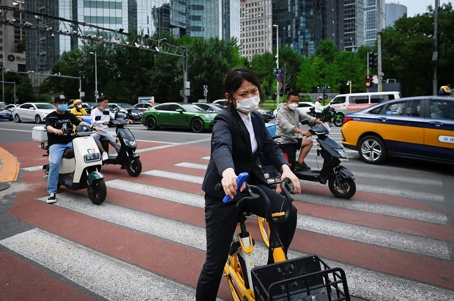 People wait to cross a street at the central business district in Beijing, China, on 8 July 2022. (Wang Zhao/AFP)