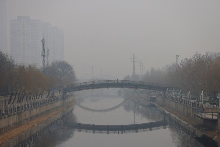 A person walks on a pedestrian bridge amid polluted air in Beijing, China, 13 February 2021. (Carlos Garcia Rawlins/Reuters)
