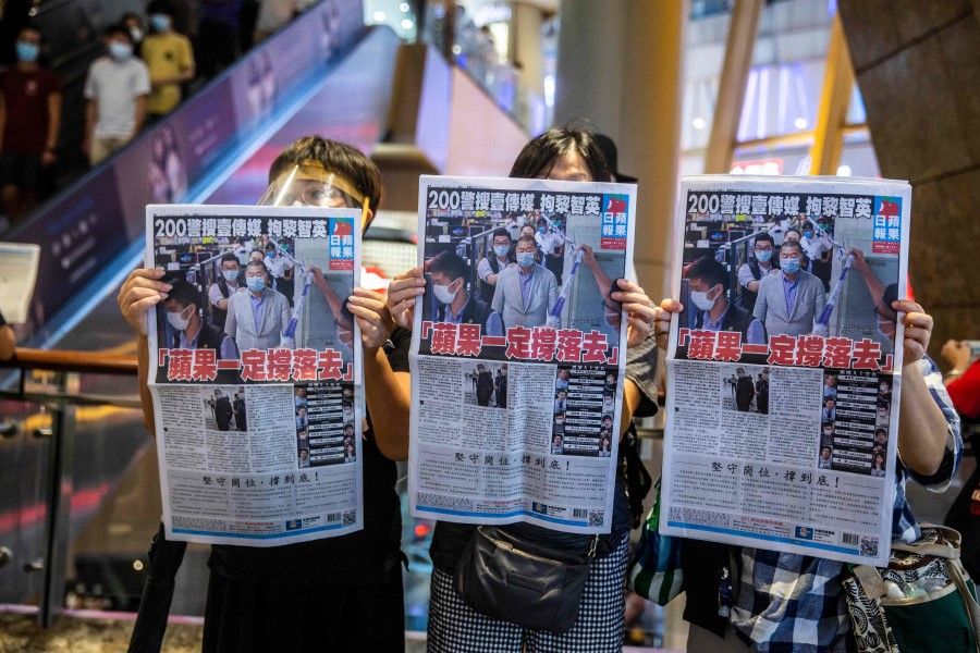 People hold up copies of the Apple Daily as they protest for press freedom inside a mall in Hong Kong on 11 August 2020, a day after authorities conducted a search of the newspaper's headquarters after the company's founder Jimmy Lai was arrested under the new national security law. (Isaac Lawrence/AFP)