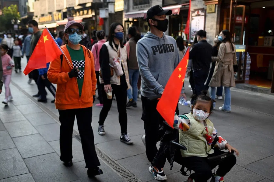 People holding Chinese flags visit a business street on the sixth day of the national day holiday in Beijing on 6 October 2022. (Wang Zhao/AFP)