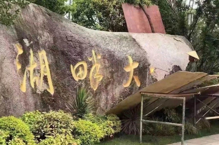 A worker removes the Chinese characters for 'Hupan University' from a stone. (Internet)
