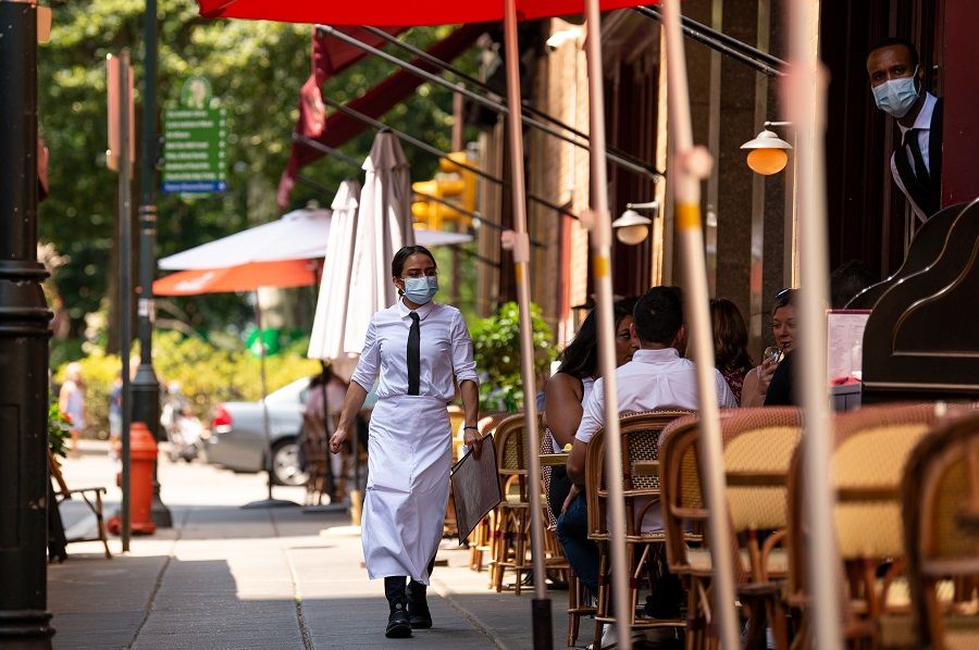 A server wearing a protective mask carries menus in the outdoor dining section of a restaurant in Philadelphia, Pennsylvania, US on 12 August 2021. (Kriston Jae Bethel/Bloomberg)