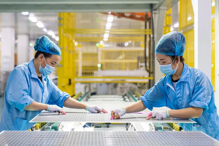 This file photo taken on 7 January 2022 shows workers producing solar photovoltaic modules used for small solar panels at a factory in Hai'an, Jiangsu province, China. (AFP)