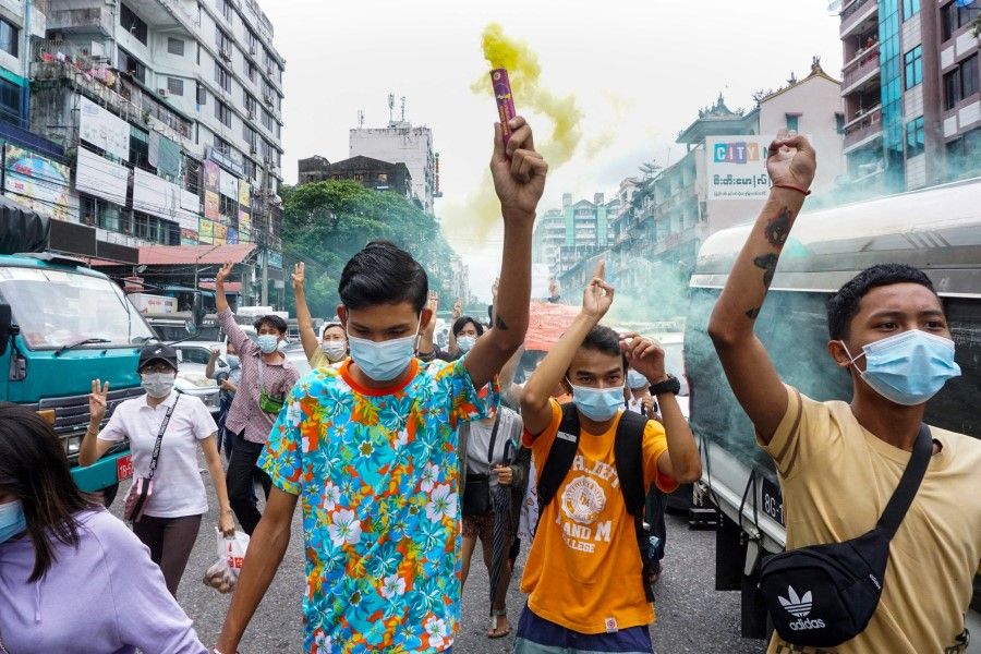 A protester holds a flare as others make the three-finger salute during a demonstration against the military coup in Yangon on 22 June 2021. (STR/AFP)