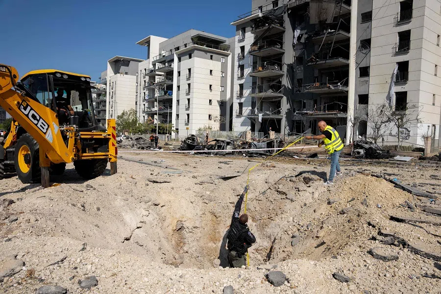 Members of the Israeli security forces check a crater on the ground at the site of an Iranian missile attack in a residential area in Beersheba in southern Israel, on 20 June 2025. (Maya Levin/AFP)