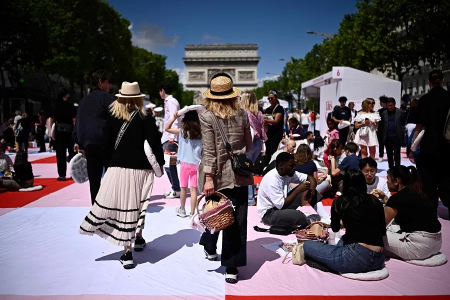 People take part in a giant open-air picnic on the Champs-Elysee avenue in Paris on 26 May 2024. 