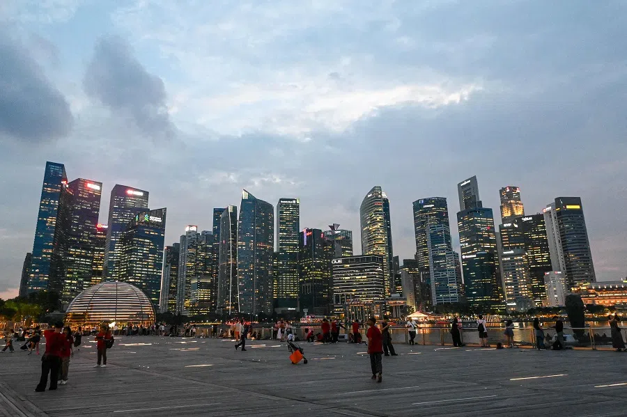 People gather along the boardwalk in front of the skyline at Marina Bay in Singapore on 27 May 2025. (Roslan Rahman/AFP)