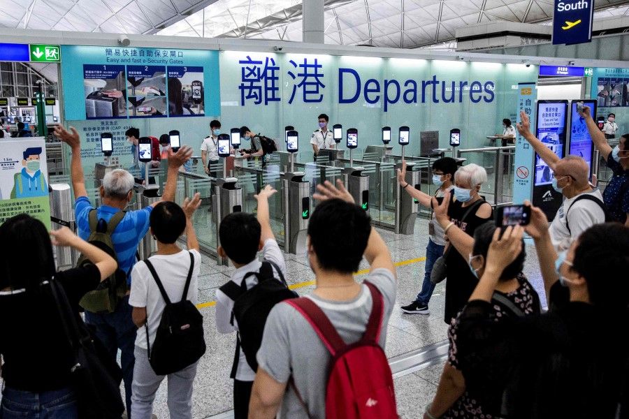 This file picture taken on 22 July 2021 shows people waving goodbye as passengers make their way through the departure gates at Hong Kong International Airport. (Isaac Lawrence/AFP)
