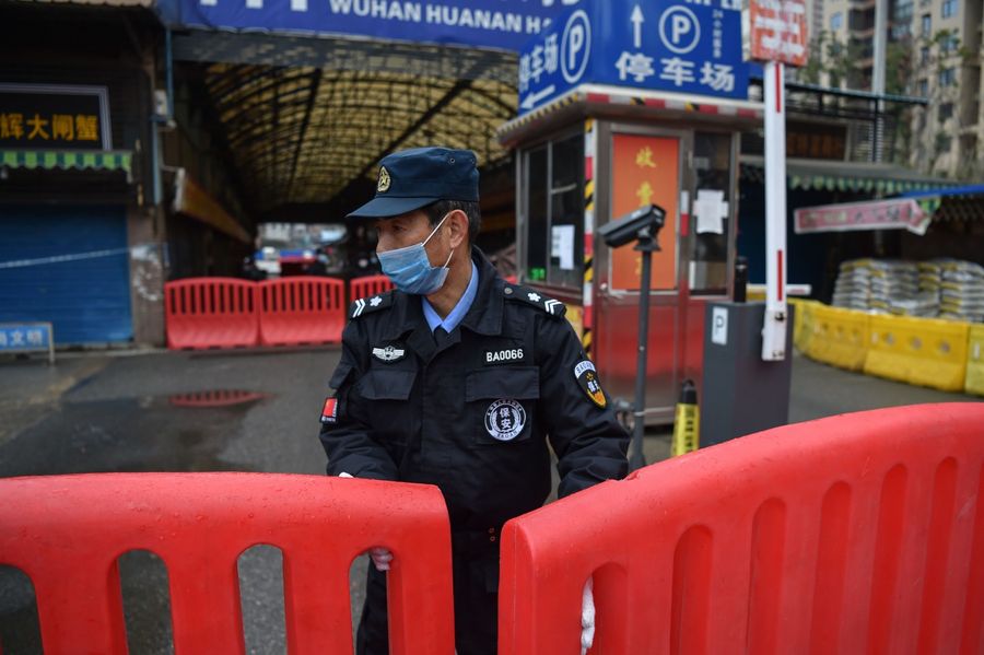 A police officer stands guard outside Huanan Seafood Wholesale market in Wuhan on 24 January 2020. (Hector Retamal/AFP)