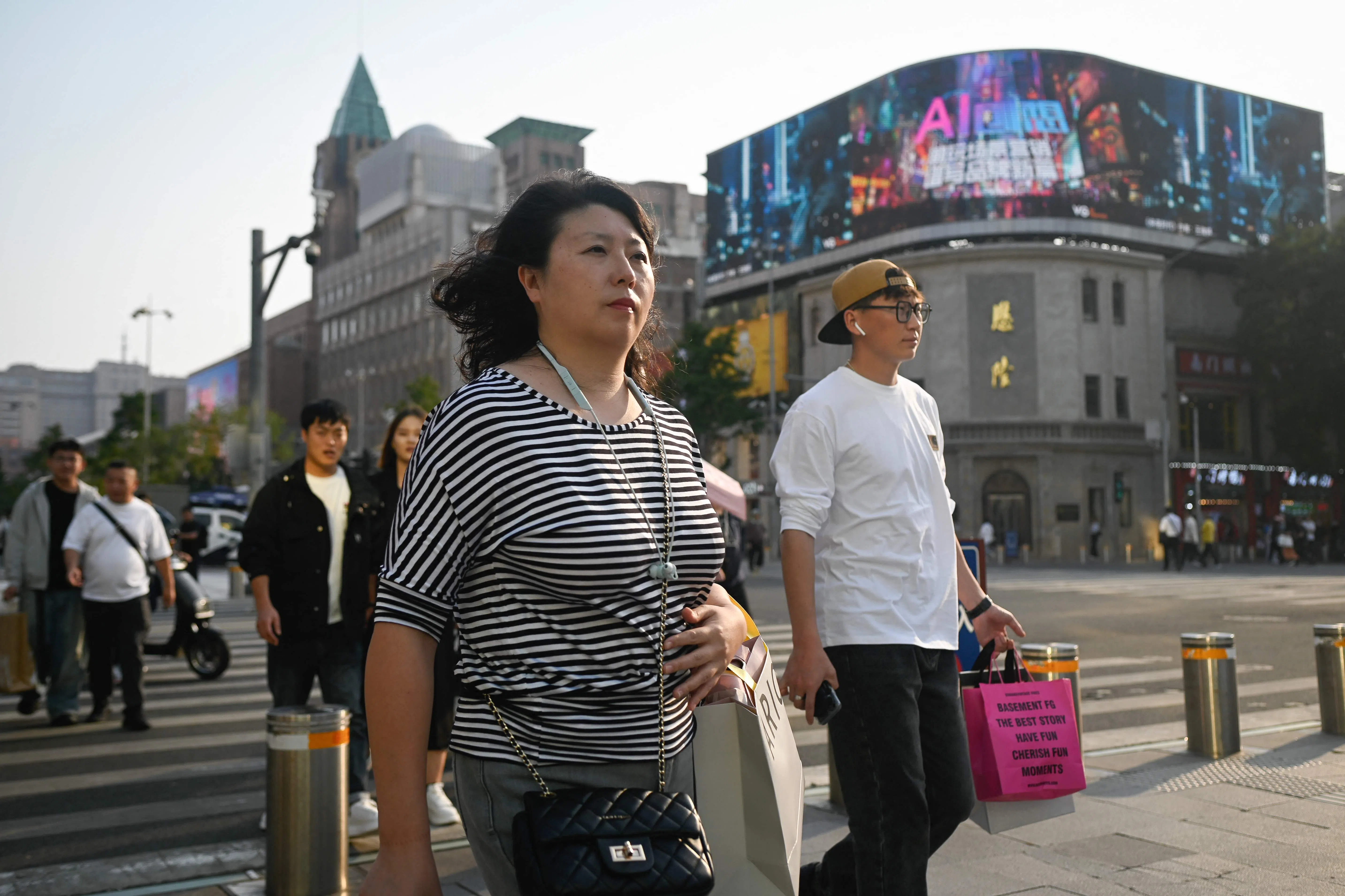 People cross a street at a business district in Beijing on 24 September 2024. (Wang Zhao/AFP)