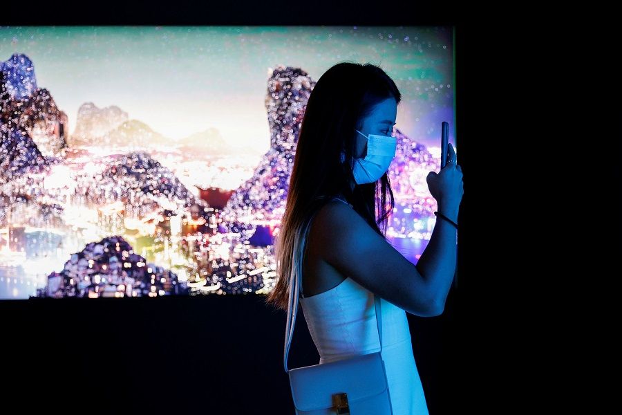 A visitor takes a photo in front of a video installation "Glows in the Night" by Chinese contemporary artist Yang Yongliang, which will be converted into NFTs and auctioned online at Sotheby's, at the Digital Art Fair, in Hong Kong, China, 30 September 2021. (Tyrone Siu/File Photo/Reuters)