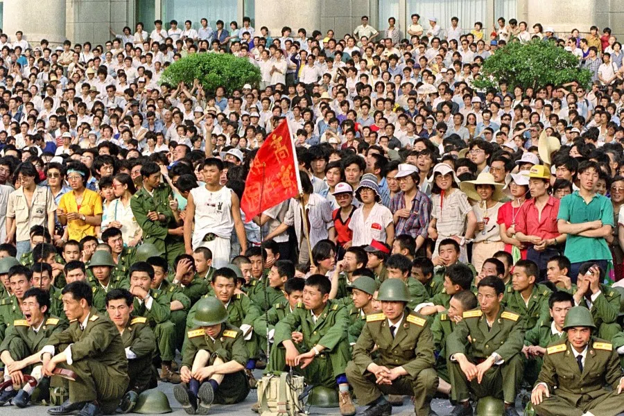 People's Liberation Army (PLA) soldiers (front) are forced by dissident students to sit in front of the Great Hall of the People in Tiananmen Square in Beijing on 3 June 1989. 4 June 2023 marks the 34th anniversary of the bloody crackdown by Chinese troops on peaceful pro-democracy protesters around Tiananmen Square in Beijing. (Catherine Henriette/AFP)