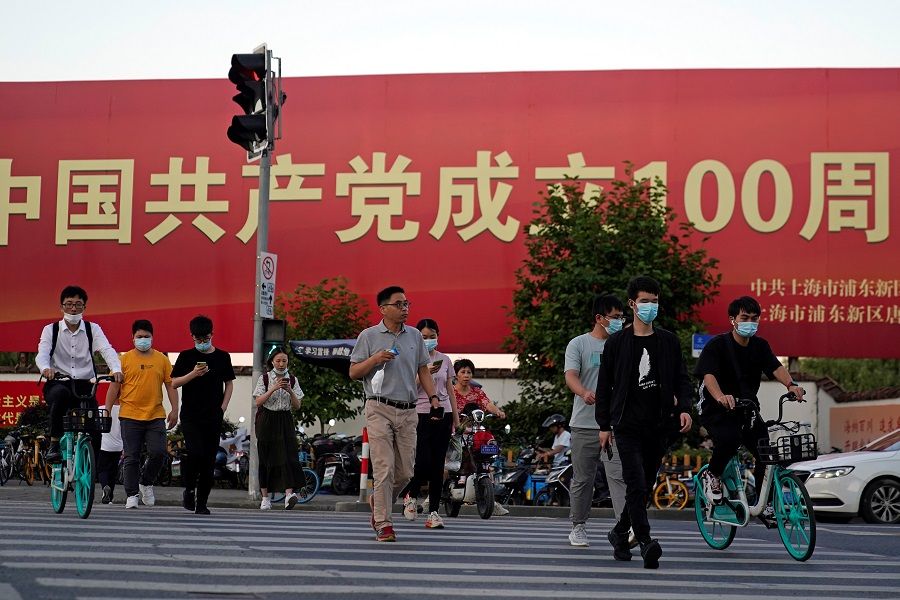 People walk on a street in front of a signboard marking the 100th founding anniversary of the Communist Party of China, ahead of the 100th anniversary of the Communist Party of China, in Shanghai, China, 22 June 2021. (Aly Song/Reuters)