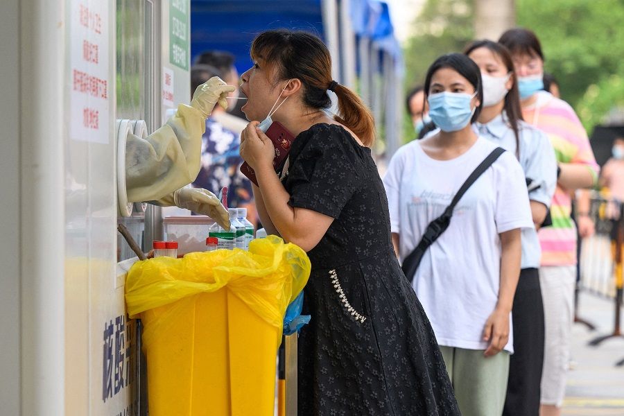 In this file photo taken on 31 July 2022, a health worker takes a swab sample from a woman to be tested for Covid-19 at a swab collection site in Guangzhou, Guangdong province, China. (AFP)