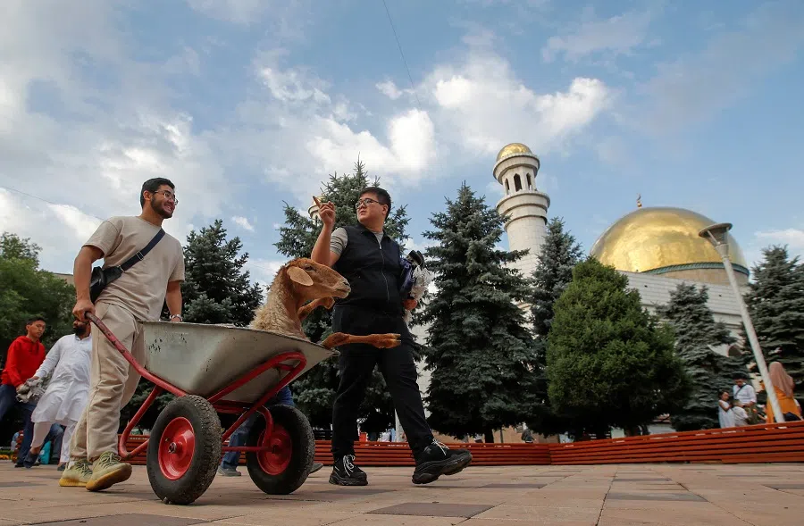 Men transport a sheep in a wheelbarrow to a slaughterhouse during the celebrations of Kurban Ait, also known as Eid al-Adha, in Almaty, Kazakhstan, 28 June 2023. (Pavel Mikheyev/Reuters)