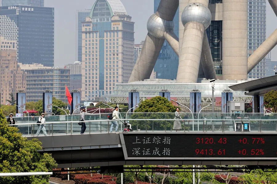 An electronic board shows Shanghai and Shenzhen stock indices as people walk on a pedestrian bridge at the Lujiazui financial district in Shanghai, China, on 8 April 2025. (Go Nakamura/Reuters)