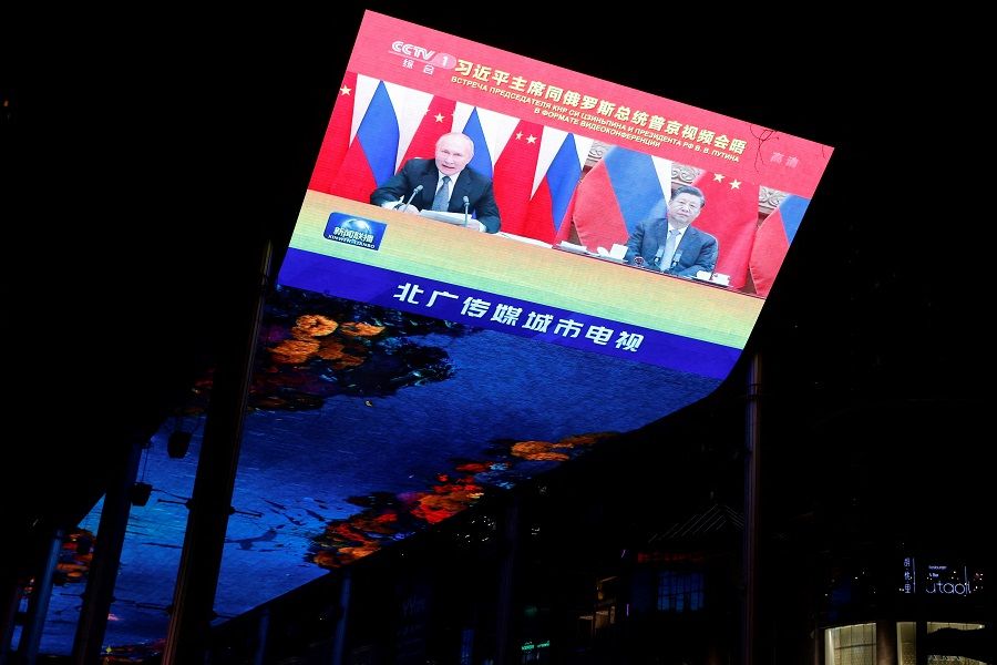 A giant screen broadcasts news footage of a virtual meeting between Chinese President Xi Jinping and Russian President Vladimir Putin, at a shopping mall in Beijing, China, 15 December 2021. (Carlos Garcia Rawlins/Reuters)