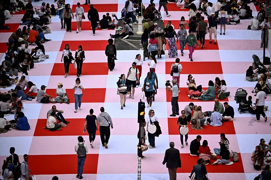 People take part in a giant open-air picnic on the Champs-Elysees avenue in Paris on 26 May 2024. (Julien de Rosa/AFP)
