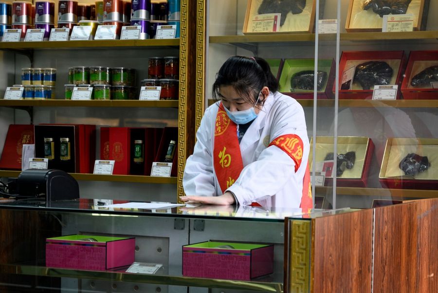 This photo taken on 1 February 2020 shows an employee wearing a protective face mask at a traditional Chinese medicine store in Beijing. (Noel Celis/AFP)