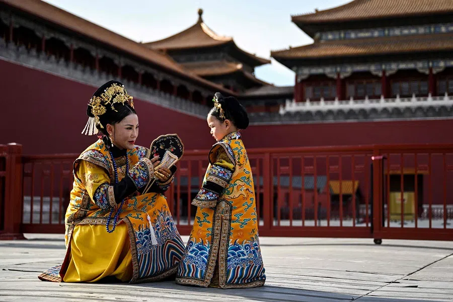 A woman and a girl wearing a traditional Chinese costume chat next to the Forbidden City during a photo session with a local photographer in Beijing, China, on 7 June 2023. (Hector Retamal/AFP)