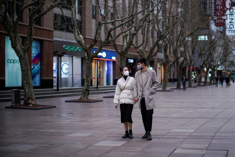 A couple wear masks at a main shopping area in downtown Shanghai, China on 21 February 2020. (Aly Song/Reuters)