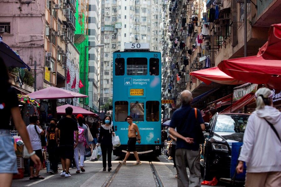 A tram makes its way through a street market in the North Point district of Hong Kong on 5 November 2021. (Isaac Lawrence/AFP)
