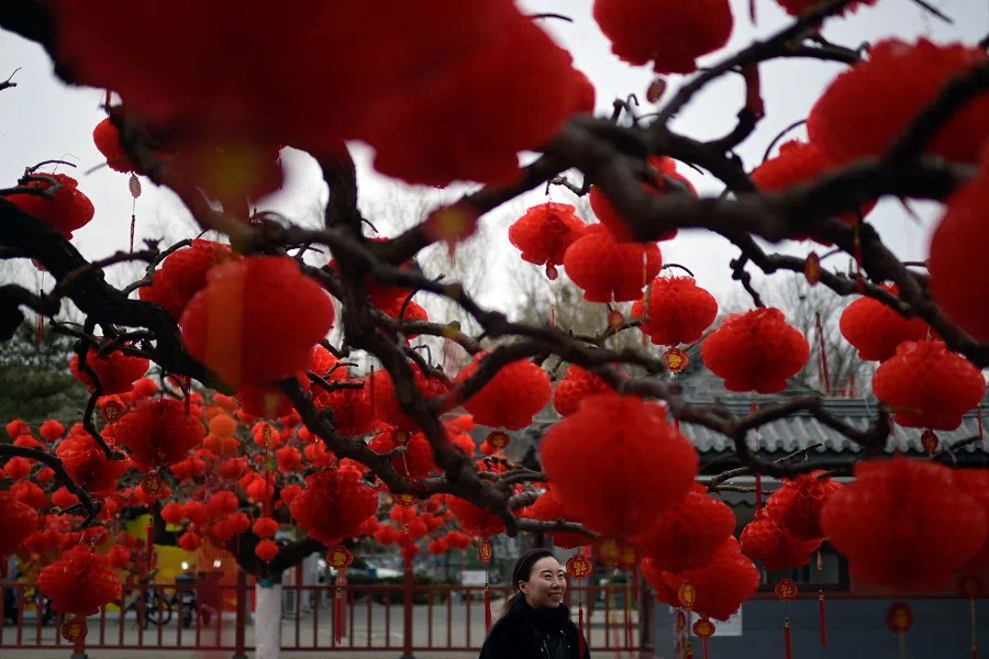 A woman walks under lantern ornaments at the festively decorated Ditan Park in Beijing on 1 February 2024. (Pedro Pardo/AFP)