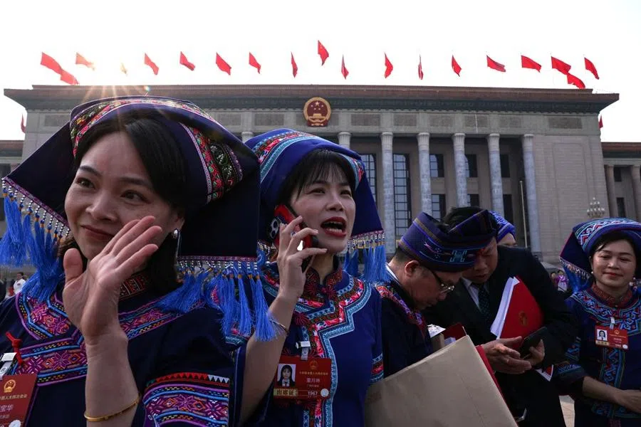Delegates in ethnic minority costumes hold documents as they leave following the closing session of the National People's Congress (NPC) at the Great Hall of the People in Beijing, China, on 12 March 2026. (Tingshu Wang/Reuters)