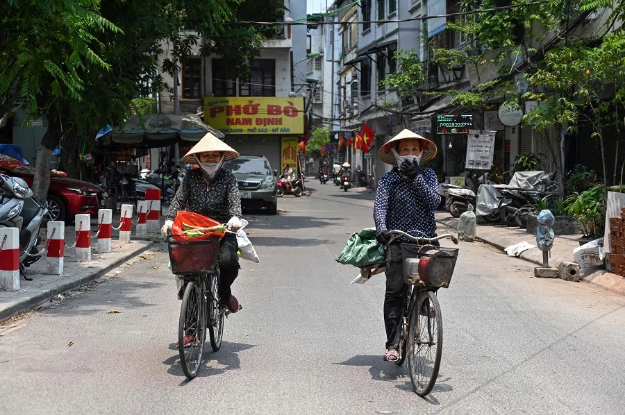 Scrap metal vendors ride bicycles on a street in Hanoi on 30 April 2024. (Nhac Nguyen/AFP)